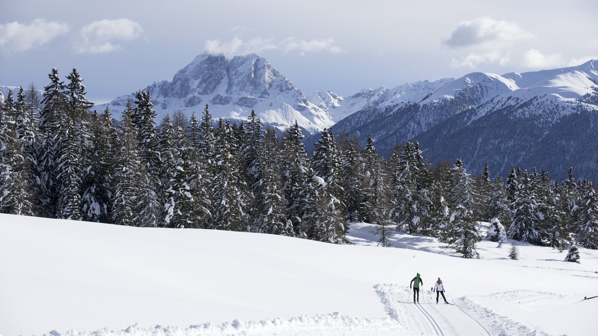 Langlauf auf der Rodenecker-Lüsner Alm Zwei Langläufer auf verschneiter Strecke vor Bergen und Wald