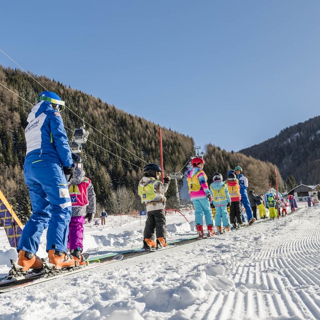 Skiing in South Tyrol: the Gitschberg Jochtal ski resort Kids and instructor on conveyor ski lift on sunny day