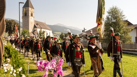 The eco-friendly way to enjoy South Tyrol Traditional parade with costumes in front of church in sunny village