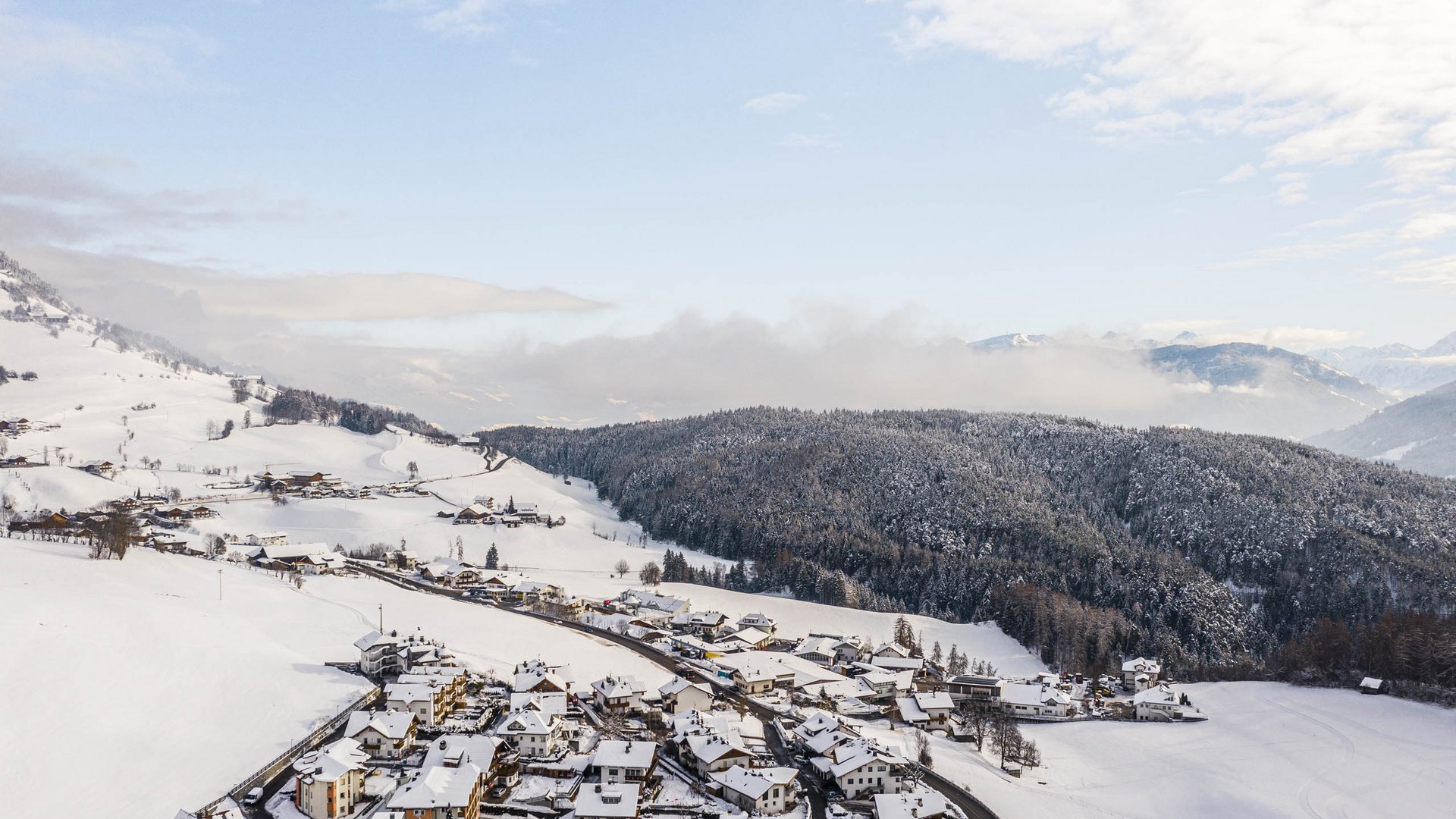 Terenten im Pustertal Verschneites Dorf am Fuß schneebedeckter Berge unter blauem Himmel