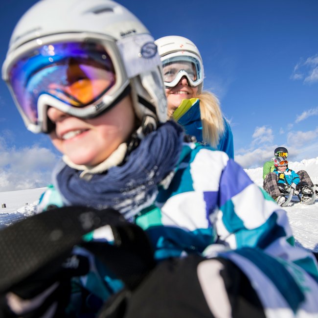 Rodeln in Südtirol Kinder und Erwachsene fahren Schlitten im Schnee bei Sonnenschein