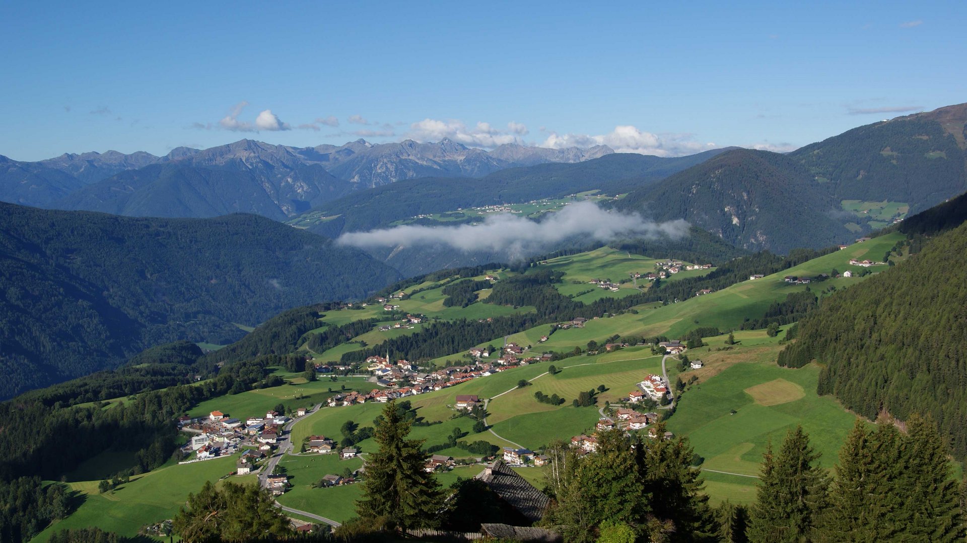 Terenten im Pustertal Bergdorf in einem grünen Tal mit Bergen und blauem Himmel