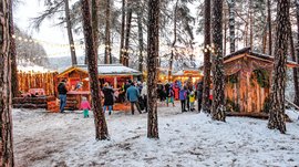 Tearna Advent Menschen bei einem beleuchteten Wintermarkt im schneebedeckten Wald
