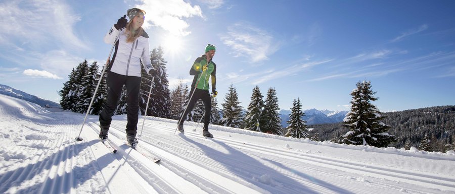 The Gitschberg webcams Two people cross-country skiing on snowy trail in bright sunlight