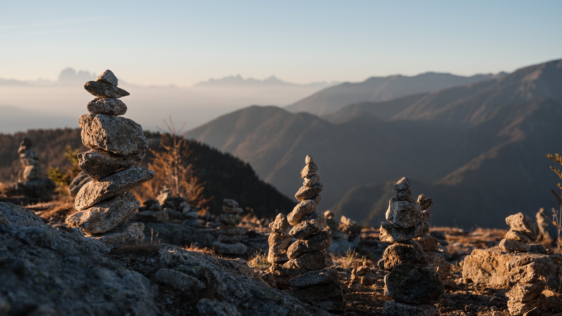 The eco-friendly way to enjoy South Tyrol Multiple stone stacks on mountain at sunrise with blurred background