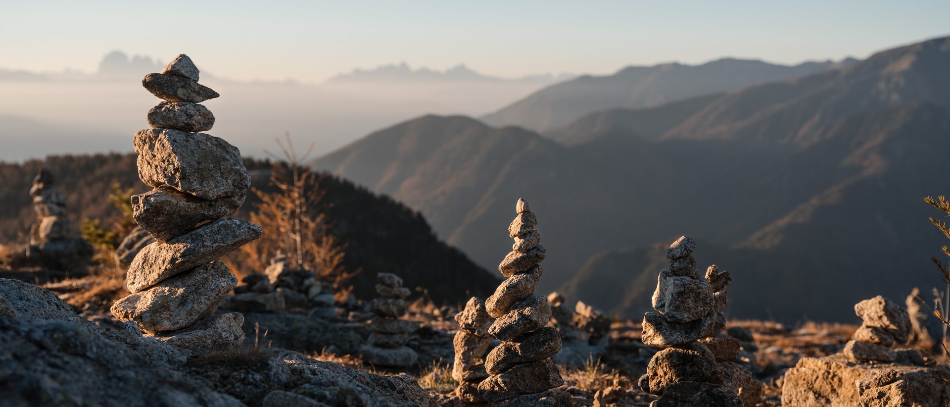 Die Almencard speziell für euch Mehrere Steinhaufen auf Berg mit Sonnenaufgang und verschwommenem Hintergrund
