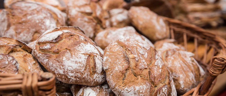 The Gitschberg webcams The picture shows a basket full of freshly baked breads with a crispy crust and a slightly floured surface. A hand is reaching for one of the breads, indicating a sale or selection.