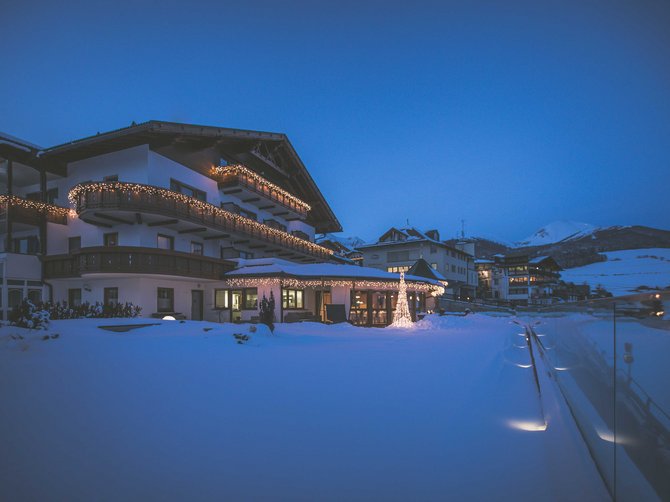 Willkommen in der Ferienregion Gitschberg Jochtal! Verschneites Haus mit Weihnachtslichtern bei Abenddämmerung in den Bergen