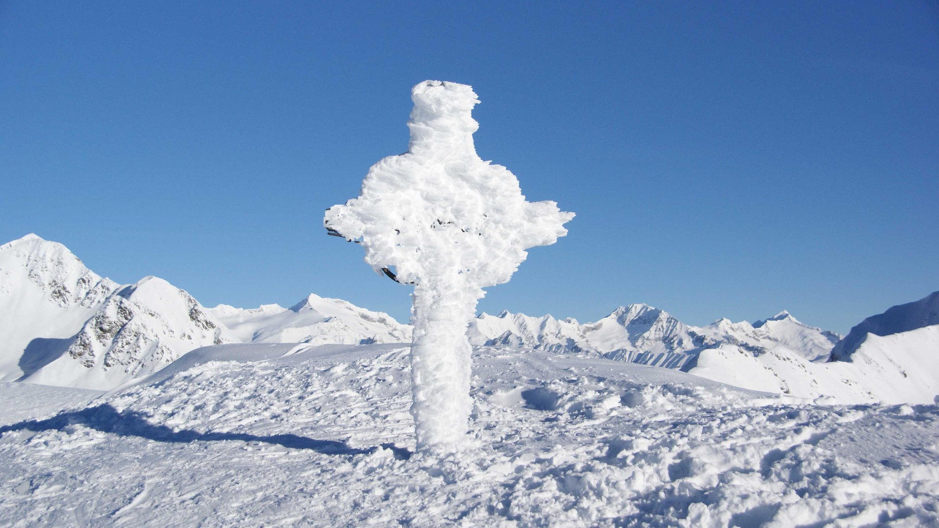 Wandern in Terenten/Pustertal Mit Schnee bedecktes Kreuz auf einem schneebedeckten Berggipfel