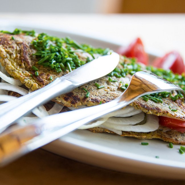 Hofschank Wieserhof Een omelet gevuld met uien en tomaten, bestrooid met verse bieslookringen.