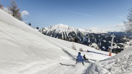 Lyžařská oblast Gitschberg Jochtal Lidé sáňkují na zasněženém svahu se sedačkovou lanovkou a horami v pozadí