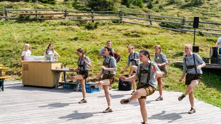 The eco-friendly way to enjoy South Tyrol Women in traditional outfits dancing on an outdoor wooden platform