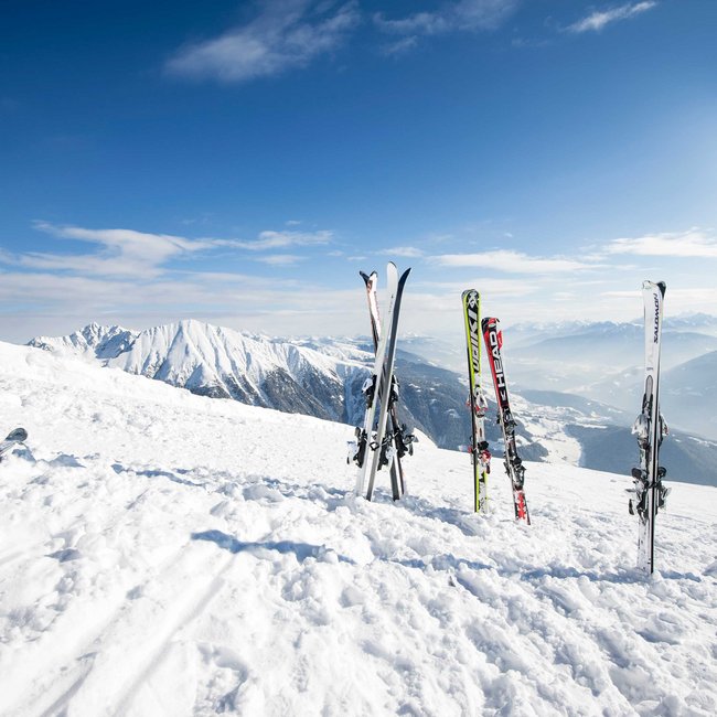 The eco-friendly way to enjoy South Tyrol Several skis standing in snow in front of snowy mountains under blue sky