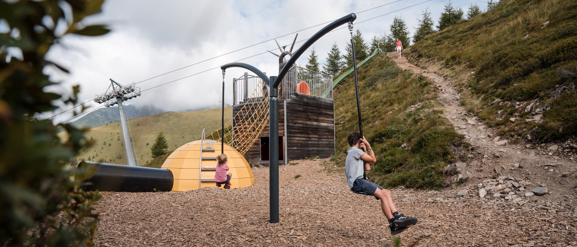 Euer Familienurlaub in Südtirol Kinder spielen auf Seilrutsche in Bergspielplatz mit Rutsche und Kletternetz