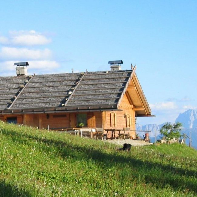 Moser Hütte Man sieht die Moserhütte von außen umgeben von Wiesen und Bergen