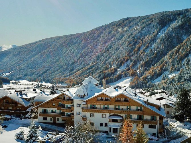 Willkommen in der Ferienregion Gitschberg Jochtal! Schneebedeckte Berghütte vor bewaldetem Berg bei Sonnenschein