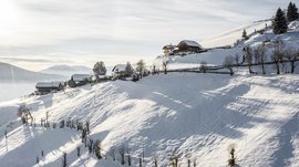 Terenten im Pustertal Schneebedeckte Hänge mit kleinen Häusern bei sonnigem Himmel