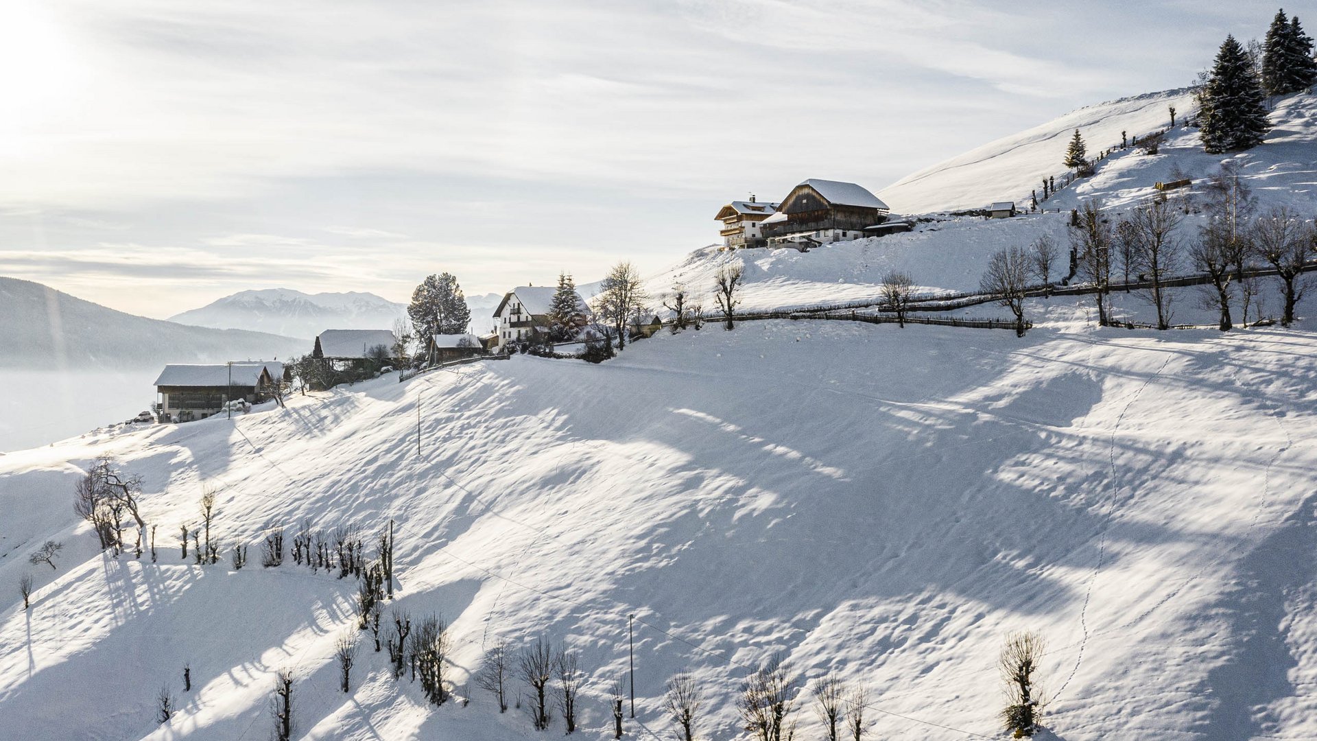 Terenten im Pustertal Schneebedeckte Hänge mit kleinen Häusern bei sonnigem Himmel