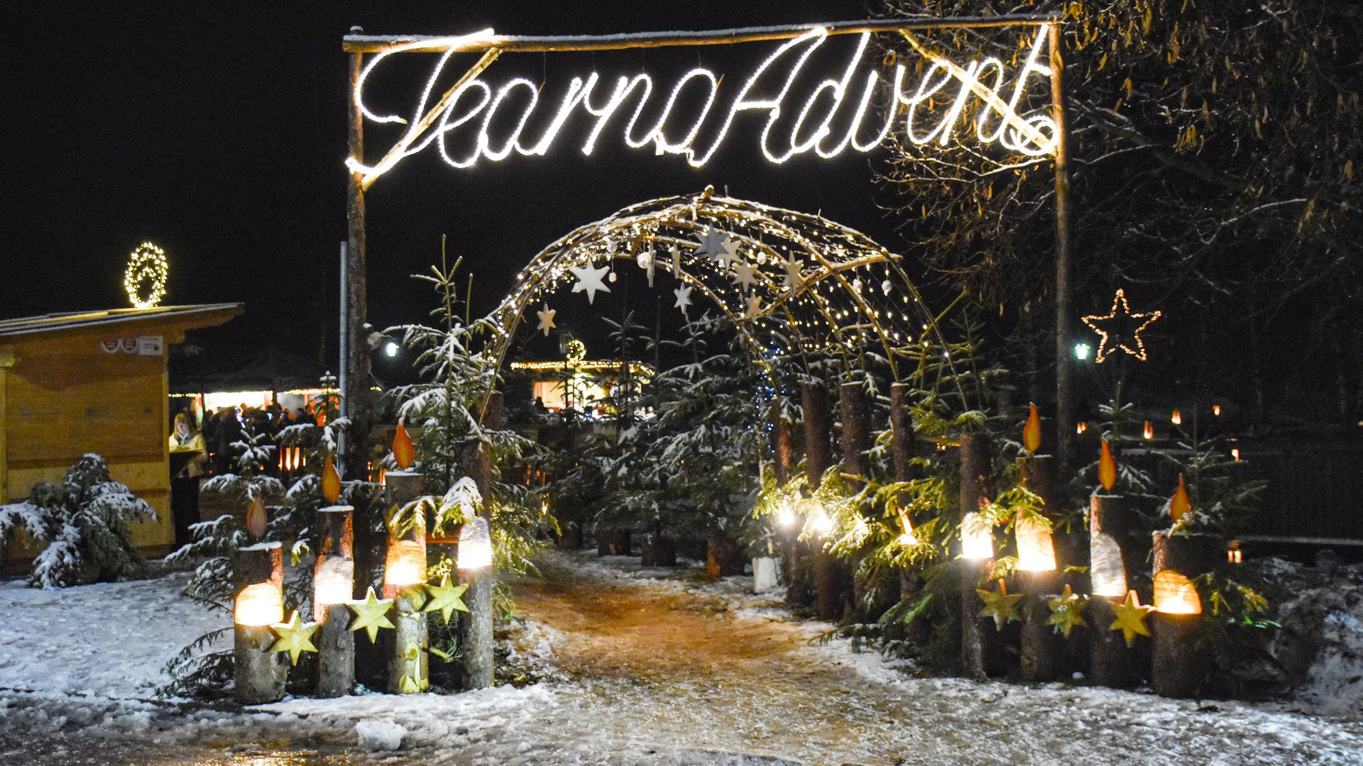 Advent in Terenten The picture shows a Christmas-decorated entrance with a large illuminated sign that says "Tearna Advent." In the background, there are more strings of lights and decorations, including a glowing star and small fir trees, set in a snowy environment.