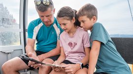Outdoor Escape on Mt. Gitschberg Man and two kids looking at a smartphone together in a chairlift