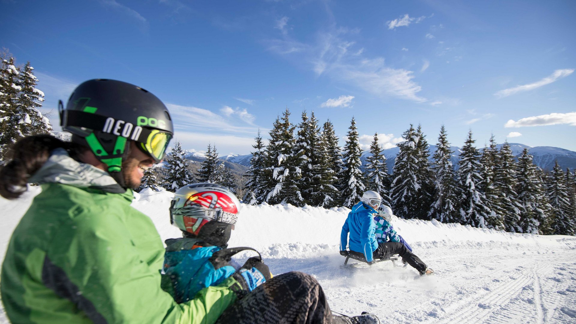 Rodeln in Südtirol Menschen beim Rodeln auf verschneiter Piste im winterlichen Wald