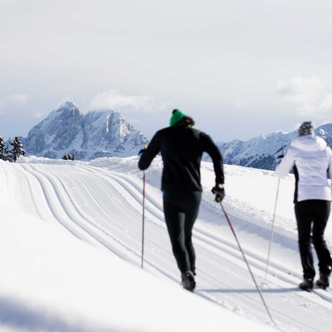 Cross-country skiing in Italy: discover Gitschberg Jochtal Two cross-country skiers on snowy trail with mountains