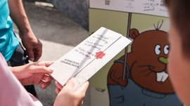 Outdoor Escape on Mt. Gitschberg Person holding flyer for Robber Hunt on Mt. Gitschberg in front of colorful board
