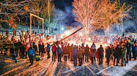 Tearna Advent Menschen versammeln sich nachts rund um eine Feuerstelle im Schnee