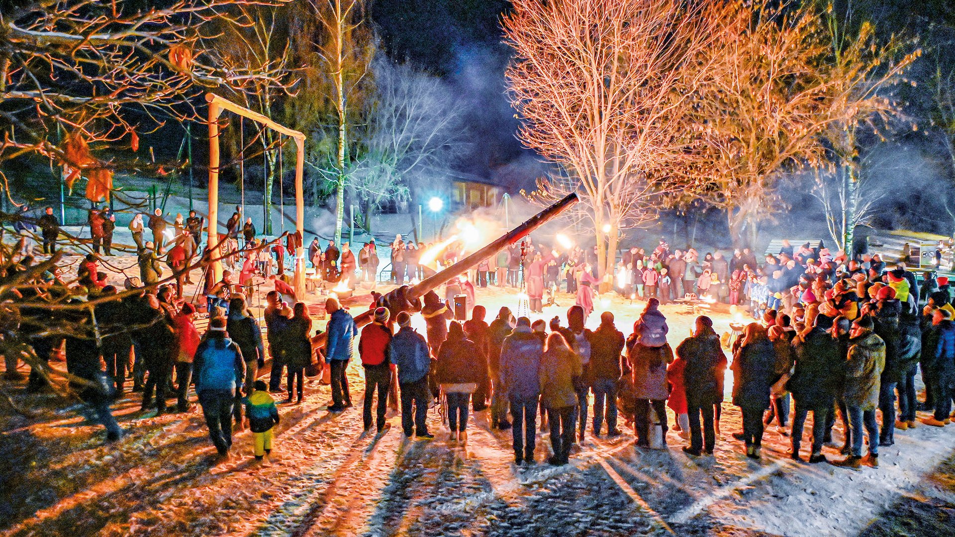 Tearna Advent Menschen versammeln sich nachts rund um eine Feuerstelle im Schnee