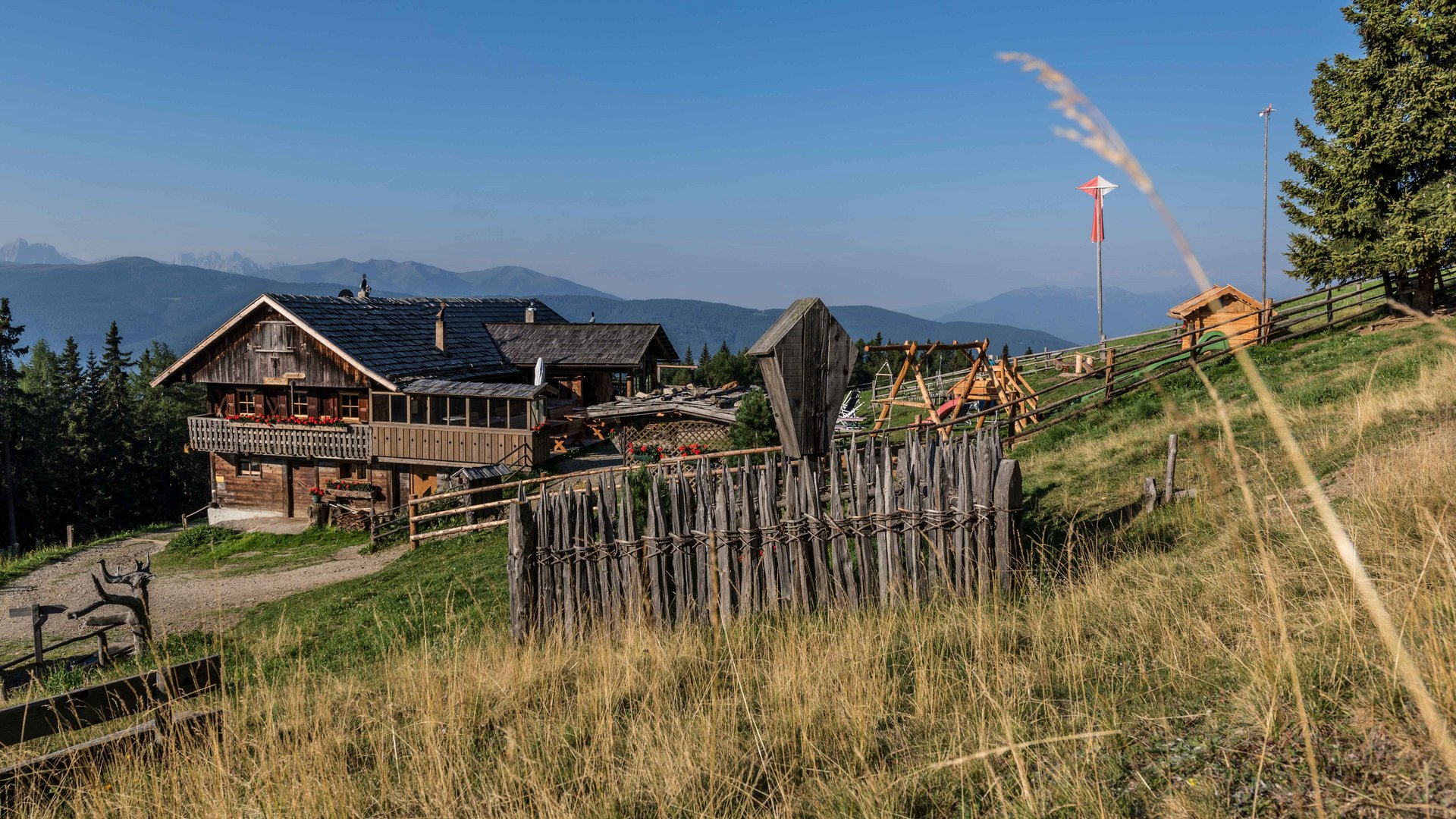 Wandern in Terenten/Pustertal Rustikales Holzhaus in den Bergen mit Zaun und klar blauem Himmel