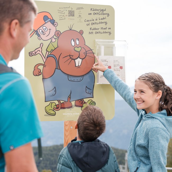 Where to spend your family holiday in Italy? Family reading sign for robber hunt on Mt. Gitschberg outdoors