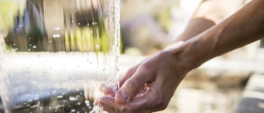Hütten in Meransen, Vals und Co. Hand fängt Wasser aus Wasserfall auf