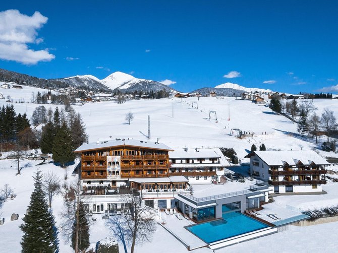 Willkommen in der Ferienregion Gitschberg Jochtal! Hotel mit Außenpool in schneebedeckter Berglandschaft unter blauem Himmel