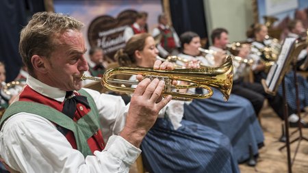 The eco-friendly way to enjoy South Tyrol Men and women in traditional costumes playing brass instruments in an orchestra