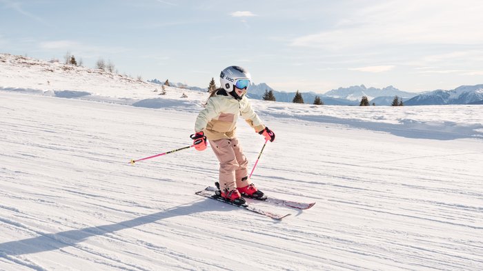 Unterkünfte Gitschberg Jochtal: Angebote Kind fährt Ski auf verschneiter Piste mit Bergen im Hintergrund