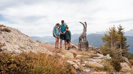 Outdoor Escape on Mt. Gitschberg Family looking at map near wooden goat sculpture in mountains