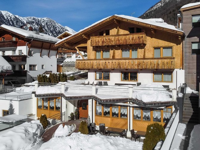 Willkommen in der Ferienregion Gitschberg Jochtal! Holzhaus im Schnee mit Bergblick unter blauem Himmel