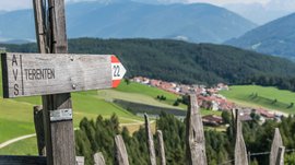 Wandern in Terenten/Pustertal Wegweiser Terenten mit Blick auf grüne Felder und Berge im Hintergrund