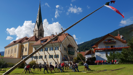 The eco-friendly way to enjoy South Tyrol Group raising a traditional maypole together in a village