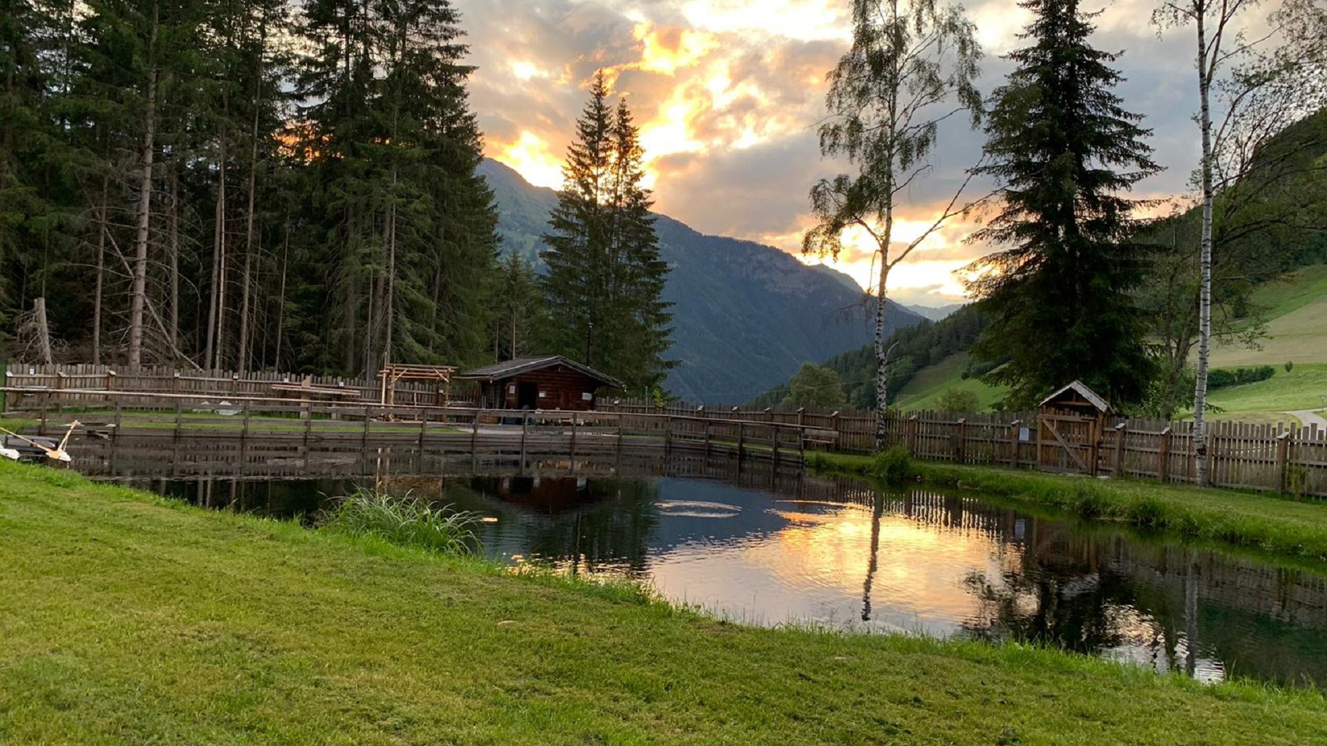 Terenten im Pustertal Sonnenuntergang über einem Teich mit Bäumen und Bergen im Hintergrund