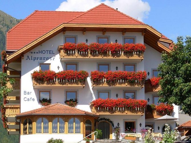 Willkommen in der Ferienregion Gitschberg Jochtal! Alpenhotel mit roten Blumen an Balkonen vor Bergkulisse