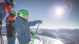 The Gitschberg panoramic platform in Meransen, Italy Three skiers wearing helmets looking at snowy mountains in sunlight