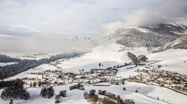 Terenten im Pustertal Schneebedecktes Dorf in den Alpen mit Bergen und Wolken im Hintergrund