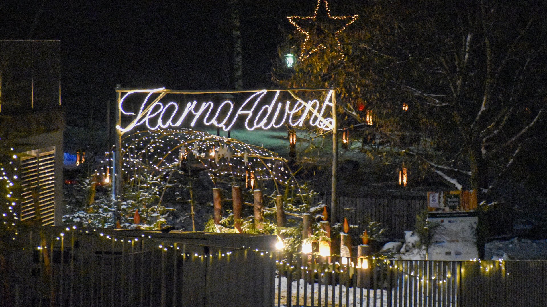 Advent in Terenten The image shows a festively lit entrance with a glowing sign "Tearna Advent." In the background, there is a large glowing star, string lights, and snowy decorations creating a Christmas atmosphere.