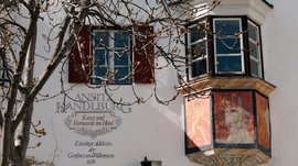 Mühlbach in the Pustertal valley Frescoed balcony and windows on historic white building with tree in front