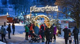 Tearna Advent Menschen besuchen einen weihnachtlichen Adventsmarkt bei Schnee am Abend