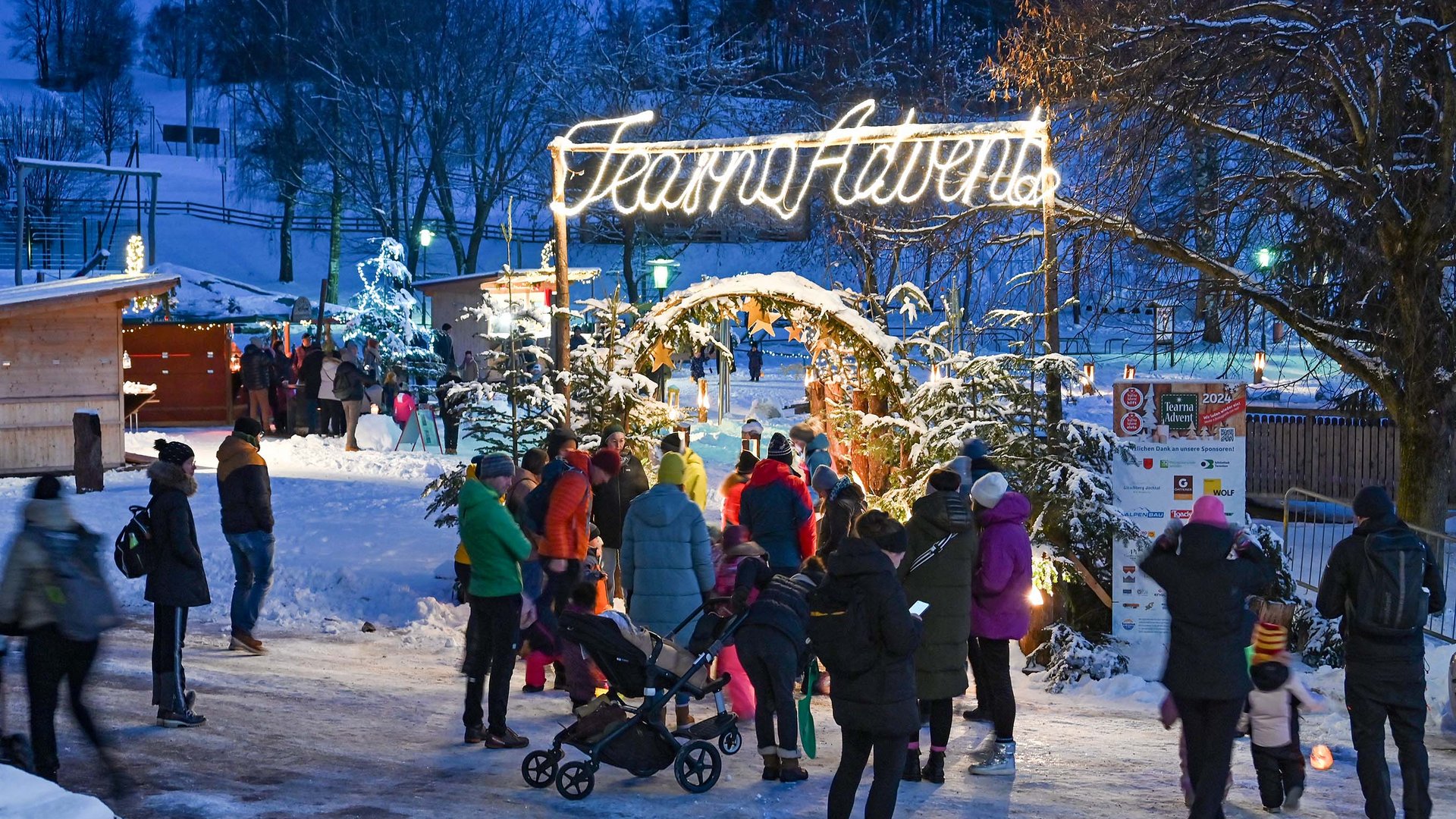 Tearna Advent Menschen besuchen einen weihnachtlichen Adventsmarkt bei Schnee am Abend