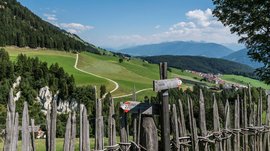 Zemní pyramidy v Terentenu Dřevěné ploty a cestovní ukazatele před zelenými kopci a horami za modré oblohy