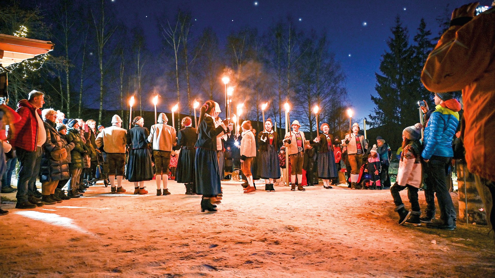 Tearna Advent Menschen mit Fackeln bei einer traditionellen Nachtveranstaltung im Freien