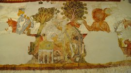 Mächtig und erhaben: Schloss Rodenegg Das Bild zeigt ein altes, teilweise beschädigtes Wandgemälde. Es stellt eine Szene mit einem Ritter in Rüstung, einem Baum und einer mythologischen Figur mit rotem Haar dar. Die Farben sind verblasst, und einige Teile des Gemäldes fehlen.